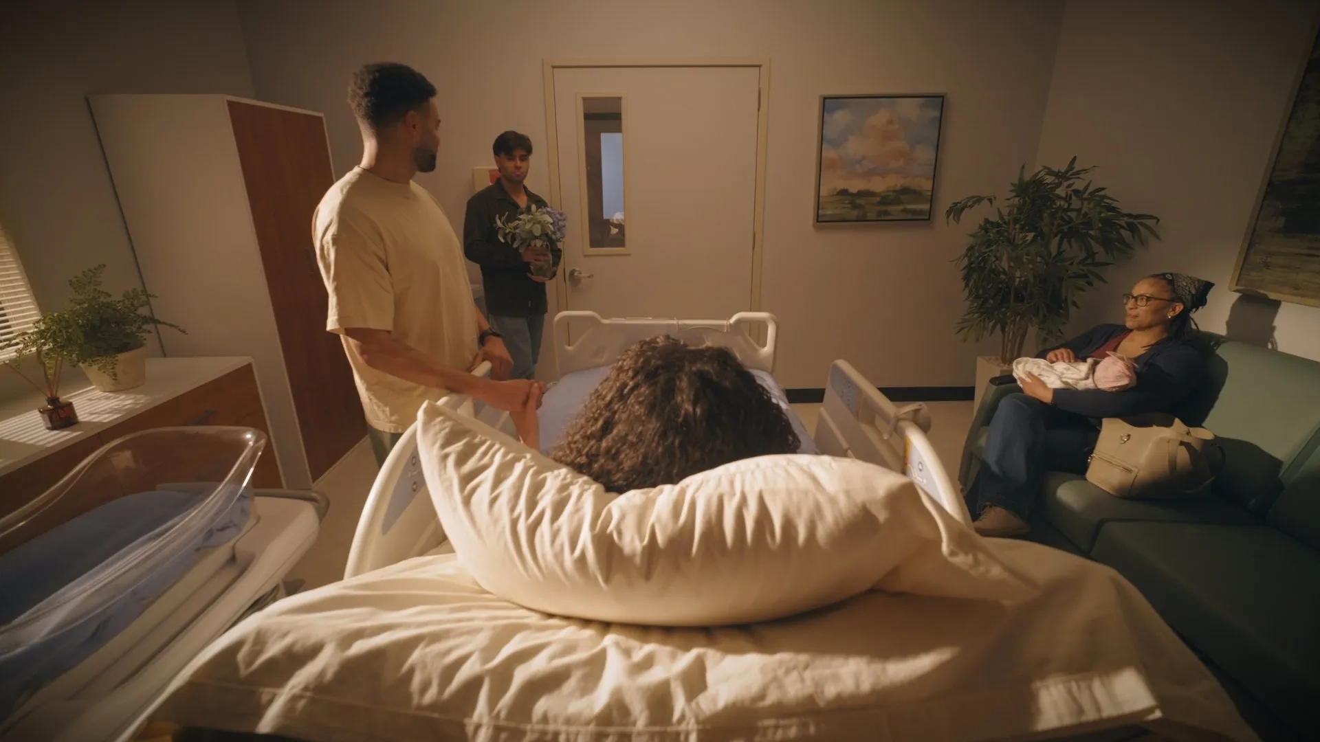 Family gathered at the bedside of a patient in a warmly lit hospital room.